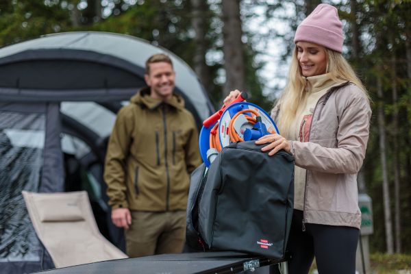 Een vrouw pakt de campingkabelhaspel uit de opbergtas